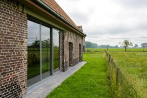 a brick building with large windows next to a field at De Grote Linde in Oostkamp