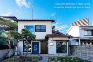 a white house with a tree in front of it at oribe guesthouse in Tajimi