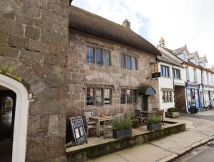 an old stone building with a table in front of it at Fox Hat Cottage in Newton Abbot