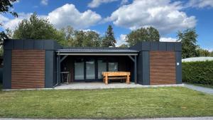 a small black house with a wooden bench in a yard at Themencamping Grünewalder Lauch in Grünewalde