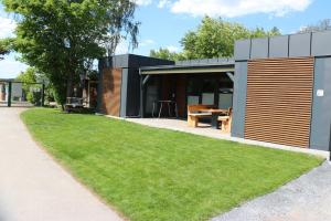 a modern house with a green lawn in front of it at Themencamping Grünewalder Lauch in Grünewalde