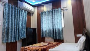 a room with a bed with blue curtains and a window at anandam stay in Vrindāvan