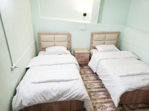 two beds in a room with white sheets at New Day Hostel in Yerevan +7 photos