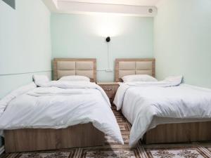 two beds in a room with white sheets and pillows at New Day Hostel in Yerevan