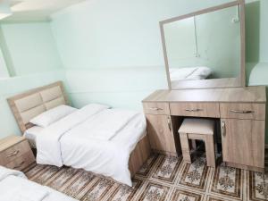a bedroom with two beds and a vanity with a mirror at New Day Hostel in Yerevan