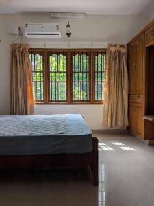 a bedroom with a bed and some windows at Veranda Villa in Angamaly
