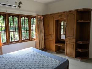 a bedroom with a bed and wooden cabinets and windows at Veranda Villa in Angamaly