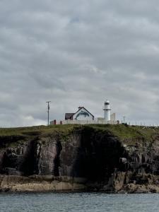a lighthouse and a house on a cliff next to the water at Waterfront Apartment in Dingle