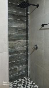 a shower with a glass door in a bathroom at Questro Apartment Hotel in eNyamazaneni