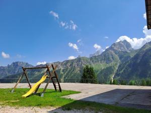 a playground with a slide in front of a mountain at Valles Vacanze - ski in & ski out in Falcade +24 photos