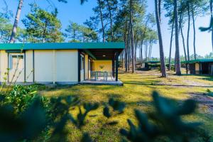 a small yellow and white house in the woods at LES COTTAGES DE LEON in Léon