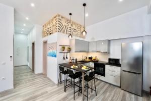 a kitchen with white cabinets and a table with chairs at Central Suites Aegina 2 in Egina