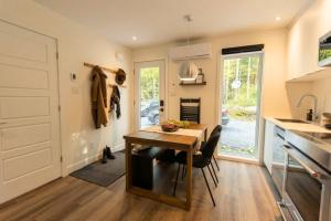 a kitchen with a wooden table and a dining room at Mini Chalet Assinie Spa Privé, Nature & Golf in Brownsburg
