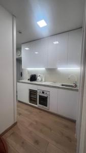 a kitchen with white cabinets and a sink at Čiurlioniada Apartment in Druskininkai
