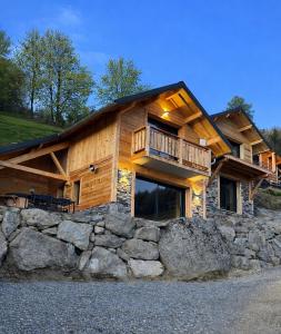 a log cabin with a balcony on top of a stone wall at Les 2 Chalets Alpins & Bains Nordiques in Saint-Michel-de-Chaillol