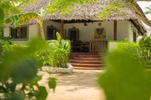 a house with a thatched roof and stairs to it at Elephant Villa Diani in Ukunda