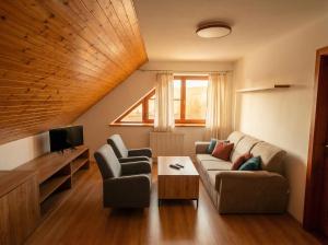 a living room with a couch and two chairs and a tv at Biely Dom in Ružomberok