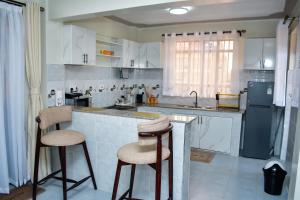 a kitchen with a counter and two stools in it at UrbanHive Naivasha Townhouse in Naivasha