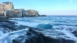 a view of the ocean with waves and buildings at Maison colette CORDOLIANI in Brando +5 photos