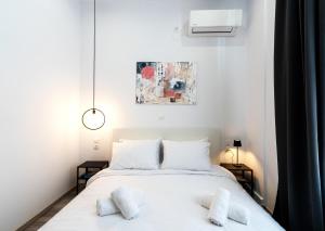 a bedroom with a white bed with two pillows at Central Suites Aegina 1 in Egina