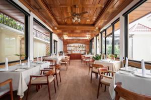a restaurant with white tables and chairs and windows at Seyna Residence in Siem Reap