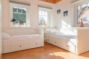 two beds in a white room with windows at Tills Hüs in Utersum