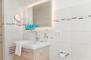 a white bathroom with a sink and a mirror at Tills Hüs in Utersum +20 photos