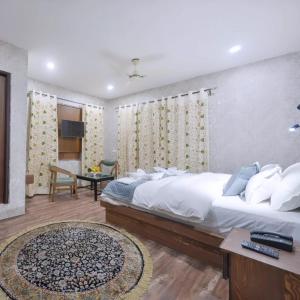 a bedroom with a large white bed and a table at Hotel Your Hive in Srinagar