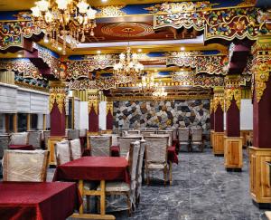 a restaurant with tables and chairs and a chandelier at Kaldan Palace in Hundar +5 photos
