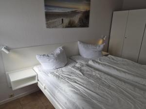 a bed with white sheets and pillows in a bedroom at Feriengarten Dahme W 22 in Dahme