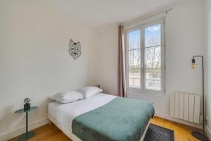 a white bedroom with a bed and a window at Charming Apartment 2BR 4P - Saint-Cloud in Saint-Cloud