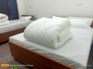 a stack of white pillows on top of a bed at Hukkam Homestay in Barkot