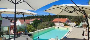 a swimming pool with two umbrellas on a house at Blue Zoon Alcobaça 2p in Carrascal