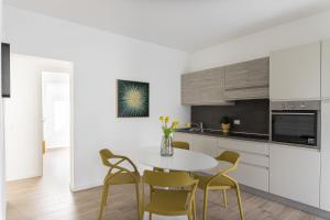 a white kitchen with a table and chairs at Maison Bellini 2 in Toscolano Maderno