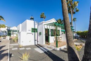 a white house with palm trees in front of it at Casa Bodega Coco in Puerto del Carmen