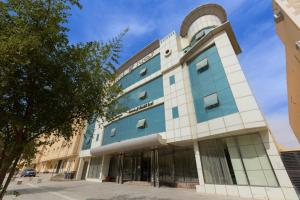 a blue and white building with a tree in front at Topaz Serviced Apartments in Riyadh