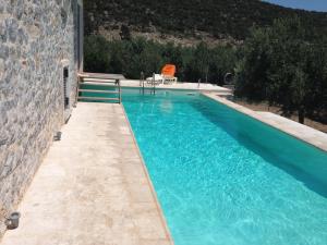 a swimming pool with blue water in front of a building at villa olivedream in Nea Epidavros