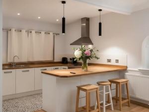 a kitchen with white cabinets and a vase of flowers on a counter at Peasehill StMichaels in Rawdon