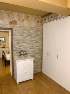 a bedroom with a brick wall and a white dresser at Domus Serena in Venafro