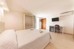 a bedroom with a white bed and a television at Porto Cesareo - Appartamenti e camere in Porto Cesareo