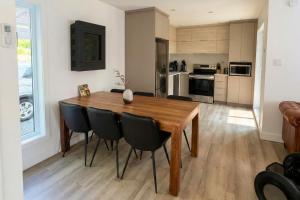 a kitchen and dining room with a wooden table and chairs at Chalet Luméo Private SPA, Golf & carling Lake in Brownsburg