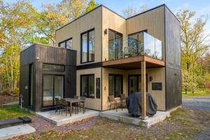 a modern house with glass doors and a table at Chalet Luméo Private SPA, Golf & carling Lake in Brownsburg