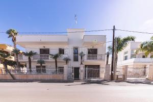a white building with palm trees in front of it at Porto Cesareo - Appartamenti e camere in Porto Cesareo