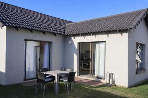 a table and chairs in front of a house at Honey Cove in Mossel Bay