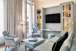 a living room with a couch and chairs and a tv at Hotel de Montesquieu in Paris