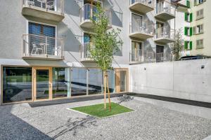 a tree in a courtyard in front of a building at MOOI Apartments Biel in Biel