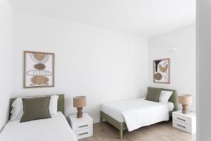 two beds in a bedroom with white and green at Maison Bellini 4 in Toscolano Maderno
