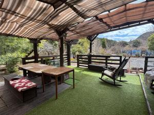 a patio with a wooden table and a bench and a table and chair at Riverside Garden -kumanokodo-chikatsuyu- in Tanabe