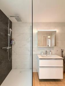 a white bathroom with a shower and a sink at Modernes Apartment - Lakeview Sunnmatte in Leissigen +13 photos