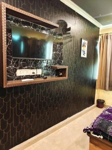a living room with a tv on a wall at Hotel Heavens in Dum-Dum Junction